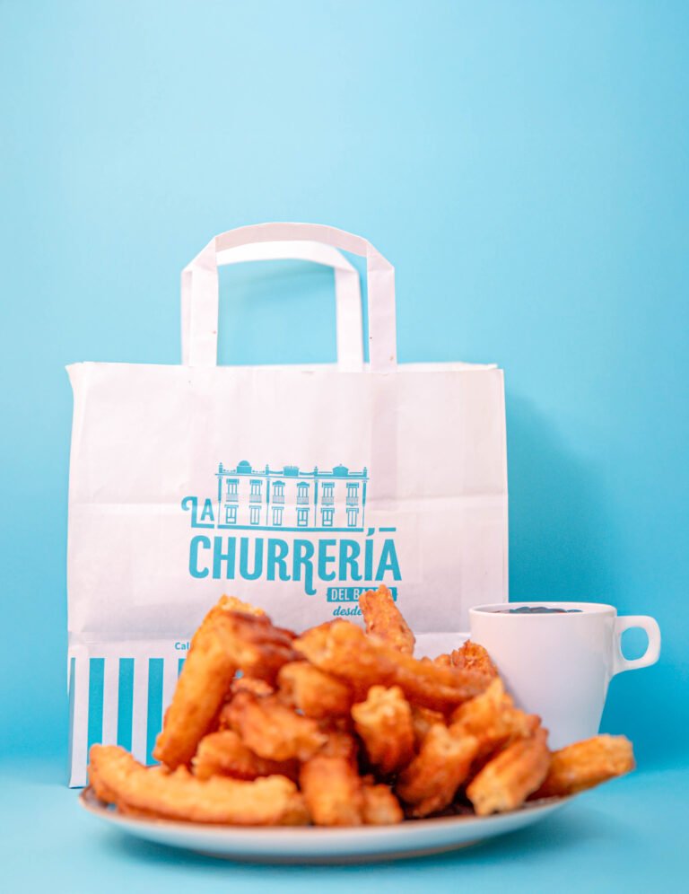 Bolsa de papel de La Churrería con churros y una taza