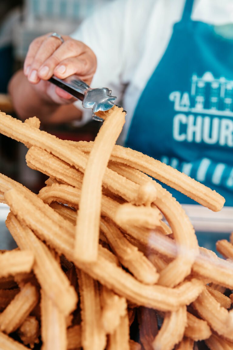 Churrera con delantal azul sirviendo churros recién hechos