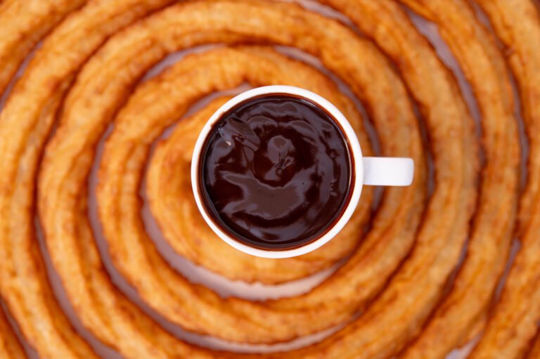 Espiral de churro con una taza de chocolate en el centro