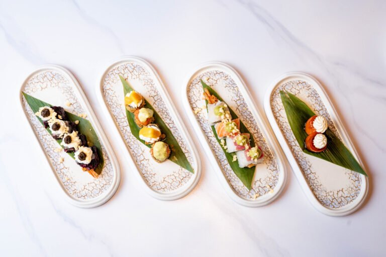 Cuatro bandejas alargadas con piezas de sushi, vista cenital