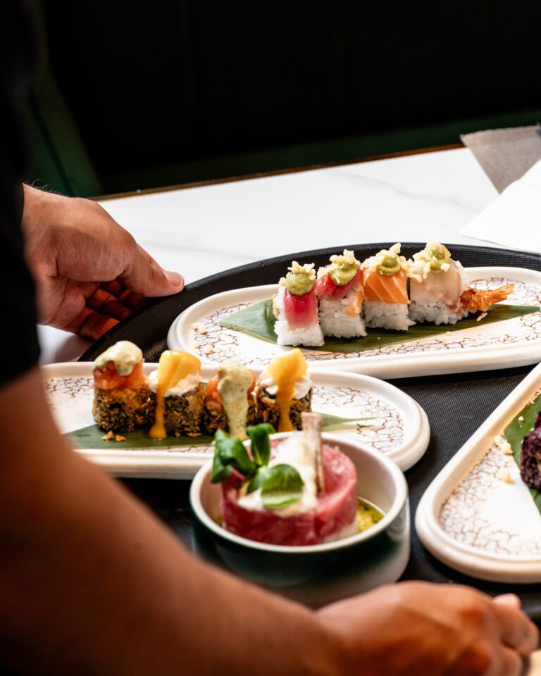 Mano colocando platos de sushi sobre la mesa
