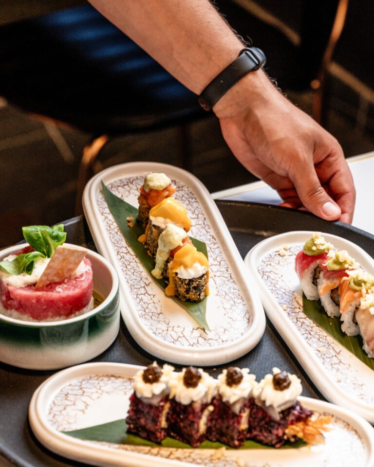 Mano sirviendo una bandeja de sushi en la mesa