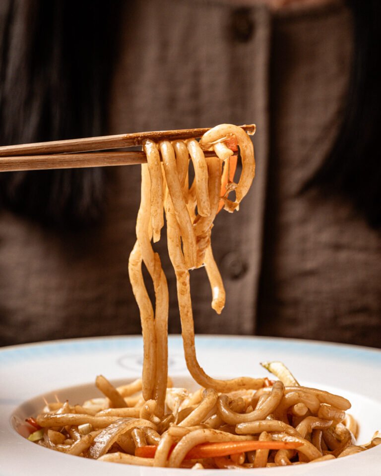 Fideos levantados con palillos sobre un plato