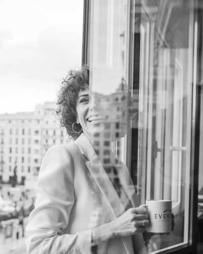 Retrato en blanco y negro de una profesional con una taza junto a una ventana