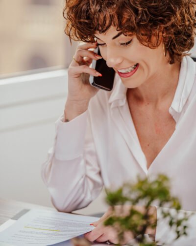 Profesional sonriendo mientras habla por teléfono en su puesto de trabajo