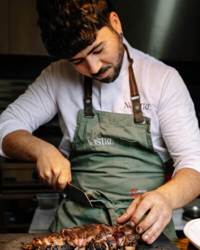Chef del restaurante Nostre cortando carne en cocina, fotografía corporativa en Valencia