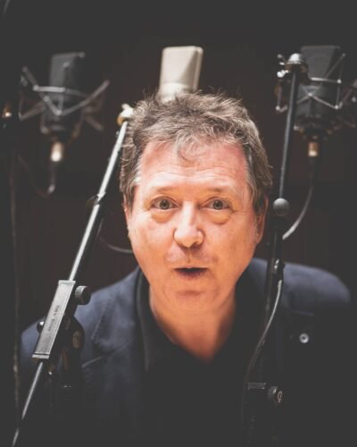 Retrato de un locutor ante micrófonos en un estudio de grabación
