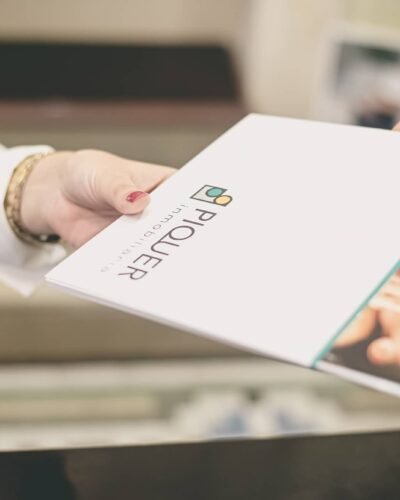 Mano entregando una tarjeta o folleto con logotipo de empresa