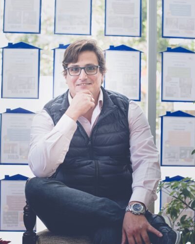 Retrato corporativo de un profesional sentado con gafas en su oficina